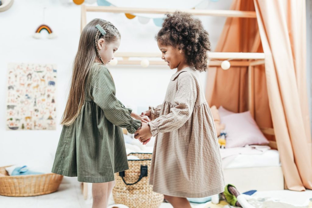 pexels photo 3662817 Two young girls holding hands and playing indoors, expressing joy and friendship in a cozy playroom.